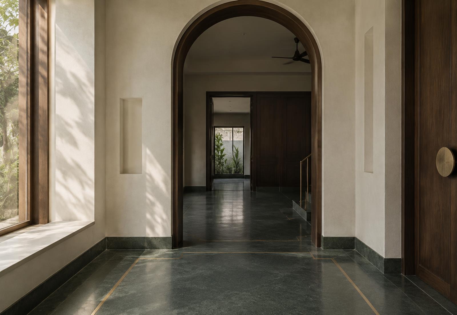 Arched teak threshold onto a honed Kota stone floor with brass inlay